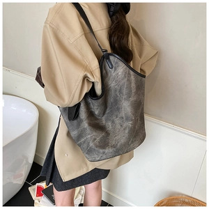 Close-up of a large dark grey vintage bucket bag with black trim on a stylish woman