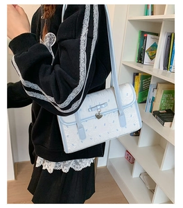 Detail of white jacquard shoulder bag with blue bow and silver heart charm pendant