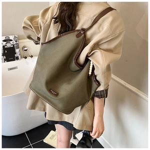 Detail view of olive canvas tote bag with brown leather trim and beaded charm decoration