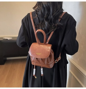 Close-up of brown vintage leather backpack with gold brand lettering and drawstring detail