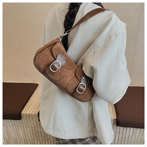 Détail du sac lune en daim marron avec boucles métalliques et bandoulière vintage