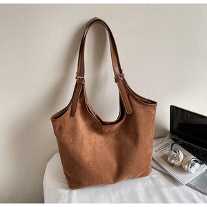 Detail of vintage brown suede tote bag with adjustable leather strap in a minimalist office setting