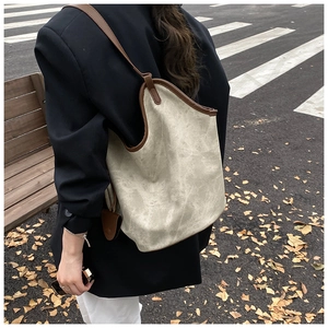 Detailed view of large vintage canvas tote bag worn over the shoulder in outdoor city setting