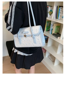 Blue bow detail and gold heart pendant on a white textured faux leather shoulder bag