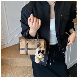 Detalle de bolso boston beige retro con colgante de oso y asas de cuero marrón