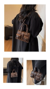 Detailed close-up of dark brown Boston bag with textured leather and front pockets