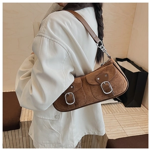 Détail du sac croissant en daim marron avec deux poches avant et boucles métalliques