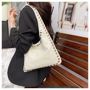 Détail d'un sac bandoulière en cuir crème avec rivets argentés décoratifs et style punk