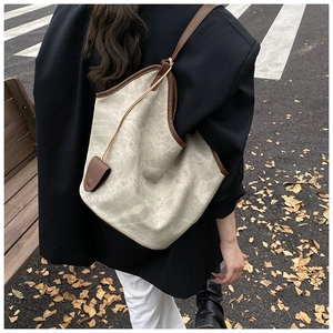 Detailed view of cream-colored cracked texture tote bag with brown leather strap