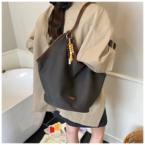 Detail of grey canvas tote with brown leather trim and colorful wooden bead accessory