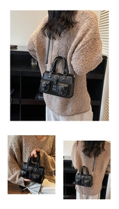 Detail of black lychee grain handbag featuring silver buckles and double front pockets