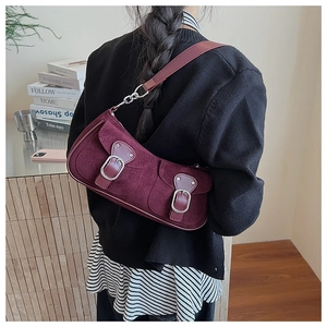 Détail du sac croissant en daim bordeaux avec poches à boucles et bandoulière en cuir