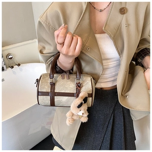 Detalle del bolso Boston de lona con ribete de cuero marrón y colgante de oso de peluche