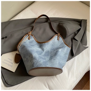 Detail of light blue textured tote bag with dark brown leather trim and handle