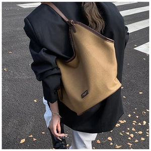 Detailed close-up of large canvas tote bag with brown leather trim and retro brand patch