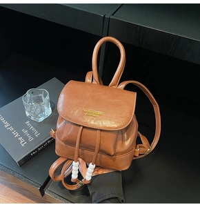 Detail of vintage brown leather mini backpack with drawstring and large white bead accent