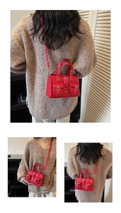 Detailed close-up of a red leather mini crossbody bag with retro buckles and dual pockets