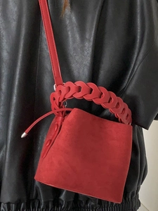 Red suede bucket bag with chunky woven handle and slim shoulder strap for women
