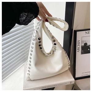 Gros plan du sac hobo en cuir blanc avec des rivets argentés sur une pile de livres