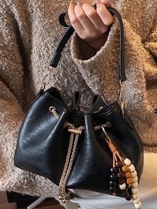 Elegant black leather drawstring bucket bag with gold chain strap and colorful beaded charm