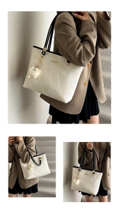 Detail view of cream leather tote bag with black straps and plush monster pendant
