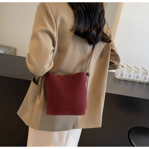 Detail of burgundy suede bucket bag styled with a khaki blazer for a chic autumn outfit