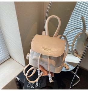 Detailed shot of cream-colored PU leather mini backpack with gold logo and beaded drawstring