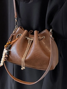 Retro dark brown bucket bag with drawstring closure and golden metal details