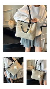 Detail of large beige tote bag with marble pattern, black leather straps and plush charm