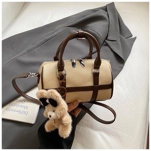 Detalle de bolso tipo almohada en lona crema con ribete de cuero y oso de peluche