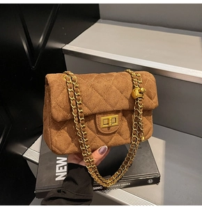 Dettaglio di una borsa in camoscio trapuntato marrone con catena dorata e fibbia in metallo
