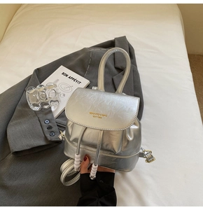 Detailed macro view of the shiny silver metallic mini backpack with gold logo lettering