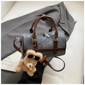 Detalle de bolso denim tipo almohada con ribetes de cuero y colgante de osito