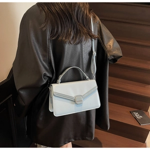 Detail of light blue leather crossbody bag with square lock worn by model on stairs