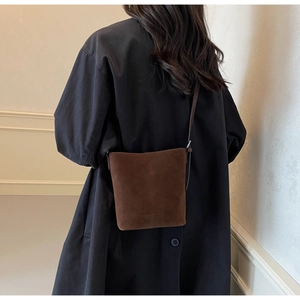 Detailed view of dark brown suede bucket bag with embossed logo and slim shoulder strap