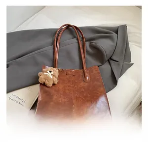 Detail of a brown tote bag with vintage texture and a cute bear plush keychain
