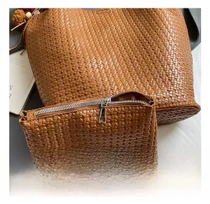 Detail showing the brown woven leather texture and silver zipper on the tote bag set