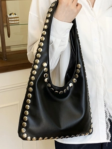 Sac hobo rétro en cuir noir avec rivets argentés et large bandoulière porté à l'épaule