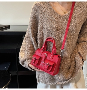 Detail of red pebble grain leather crossbody bag with multiple pockets and silver hardware