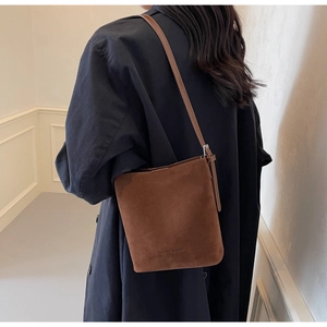 Back view of a brown suede bucket bag worn over a dark navy coat for a stylish look