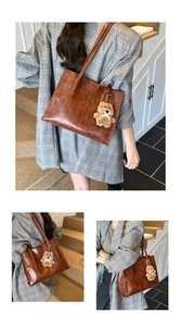 Detail of vintage brown tote bag with glossy texture and plush bear charm pendant