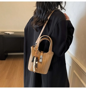 Détail du sac seau tressé marron avec fermoir argenté et breloque décorative en perles