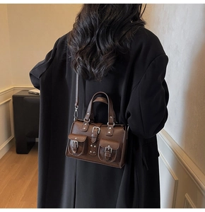 Detailed macro view of dark brown lychee textured leather bag with metallic buckles