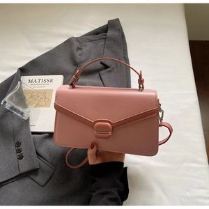 Close-up of pink PU leather handbag with square lock buckle next to a gray blazer
