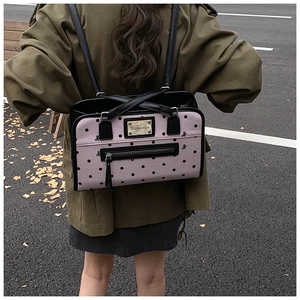 Pink polka dot backpack with black leather trim and golden logo plate on model back
