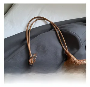 Macro shot of brown woven leather texture and slender double handles on a bucket bag