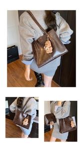 Detail view of brown vintage leather tote bag with teddy bear charm and inner pouch