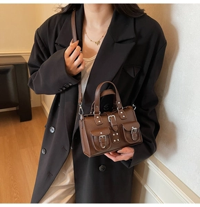 Brown lychee grain leather handbag detail with silver buckles and adjustable strap
