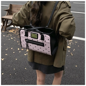 Pink and black polka dot shoulder bag shown with adjustable straps and zipper detail