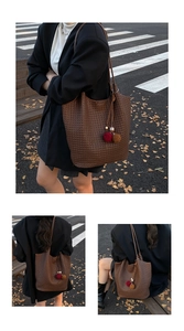 Detailed view of dark brown woven tote bag featuring a decorative furry ball pendant